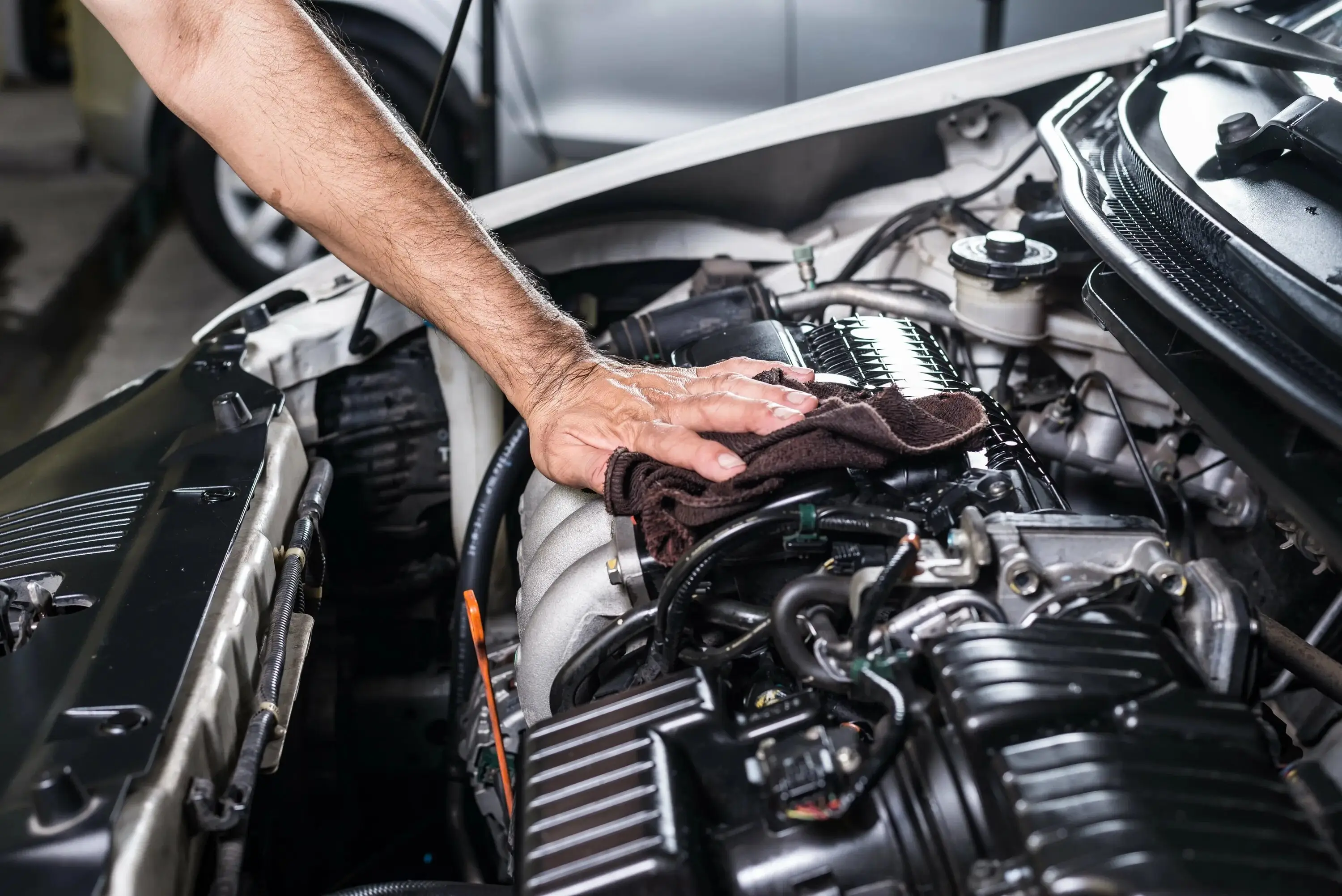 A mechanic carefully installing a performance part into an engine bay.